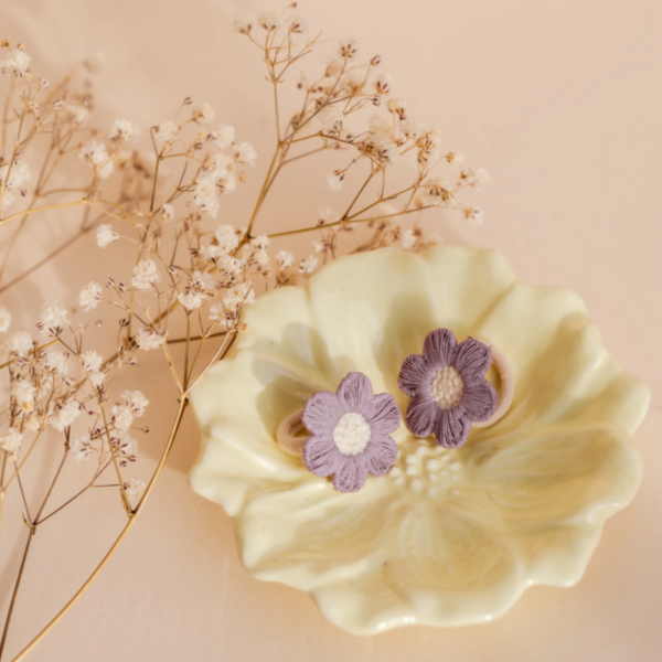 Paarse Ninte elastiekjes met bloemmotief op een sierlijk schaaltje, perfect voor schattige en comfortabele hair-do's.