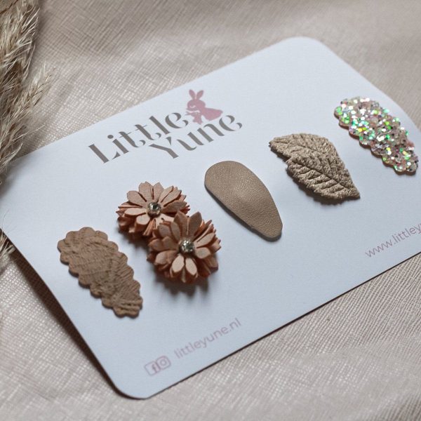 Set Lara met vijf beige antislip haarspeldjes in verschillende vormen en structuren, waaronder een bloem, blaadje en glitterspeldje, op een kaart van Little Yune.