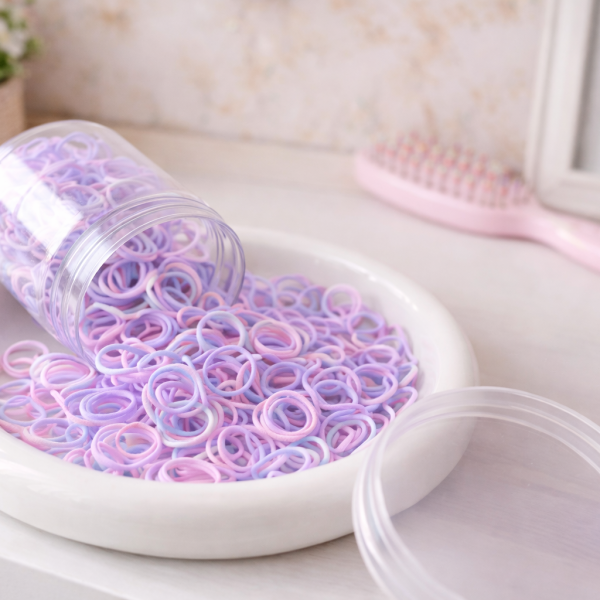 Pastelkleurige mini haarelastiekjes in zachte tinten roze, mint, perzik en crème, gepresenteerd in een schaaltje in een meisjeskamer.