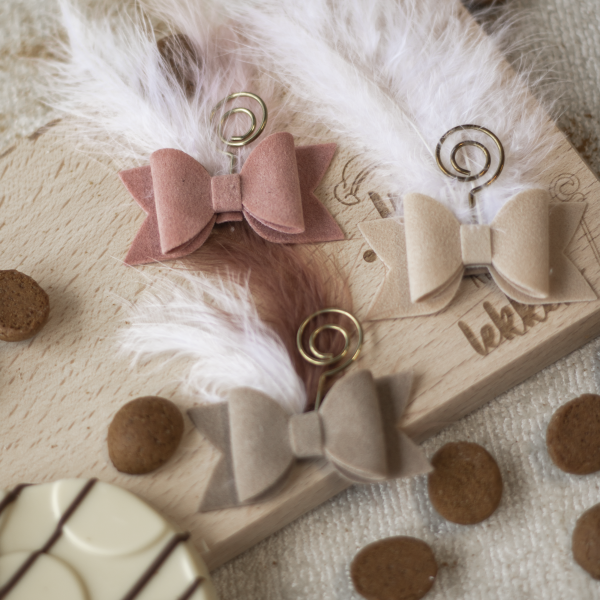 Anti-slip haarspeldjes met vilten strik en veertje in sinterklaasthema, liggend tussen kruidnoten en chocoladeletter.