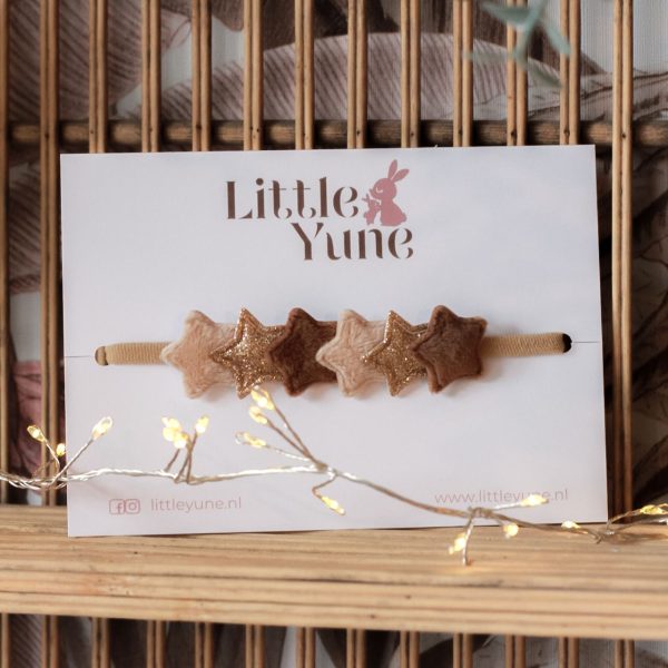 Baby haarbandje Stella van Little Yune – zachte fluwelen band met vijf sterretjes in beige, bruin en goud op kaartje met Little Yune-logo, sfeervol gefotografeerd met kerstlichtjes.