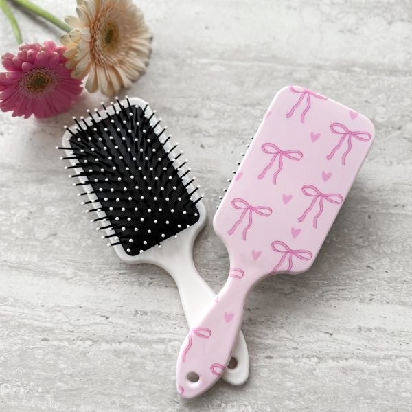 Roze haarborstel met strikjes en hartjes print, zachte pinnetjes voor het voorzichtig ontklitten van kinderhaar zonder te trekken.