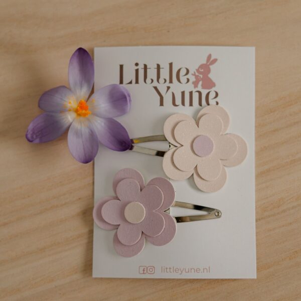 Twee madelief bloem haarspeldjes in zachte pastelkleuren op 4 cm klikklakspeldjes van Little Yune, gestyled bij een meisje hairdo met plukjes haar vastgezet.
