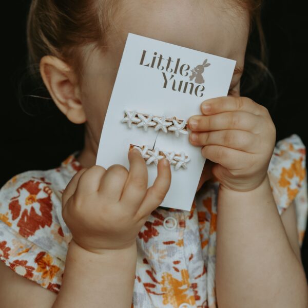 Zeester Sparkle van Little Yune met twee witte glitter zeesterretjes op goudkleurige 4 cm alligatorspeldjes voor meisjes, perfect voor zomerse kapseltjes en strandlookjes.