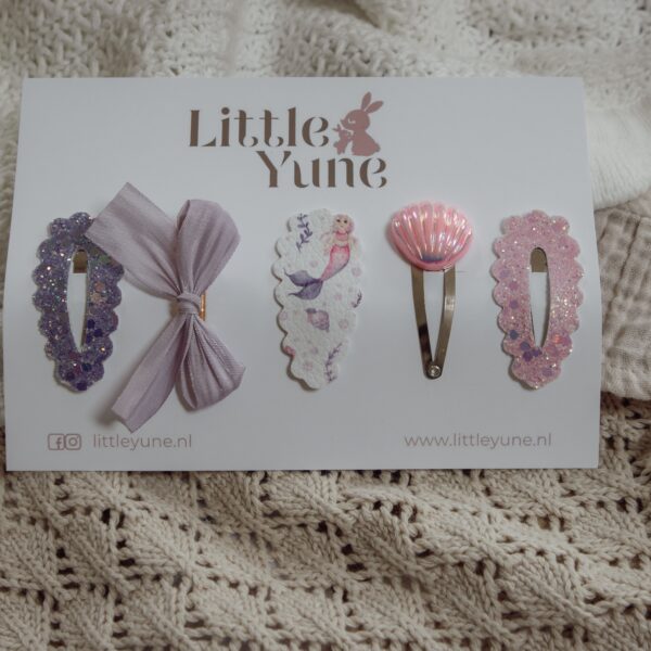 Setje Livia Pearl van Little Yune met vijf 4 cm klikklak speldjes in zeemeermin thema, met lila glitter, een zachte lila strik, een zeemeermin print, een roze schelpje en roze glitter voor meisjes.
